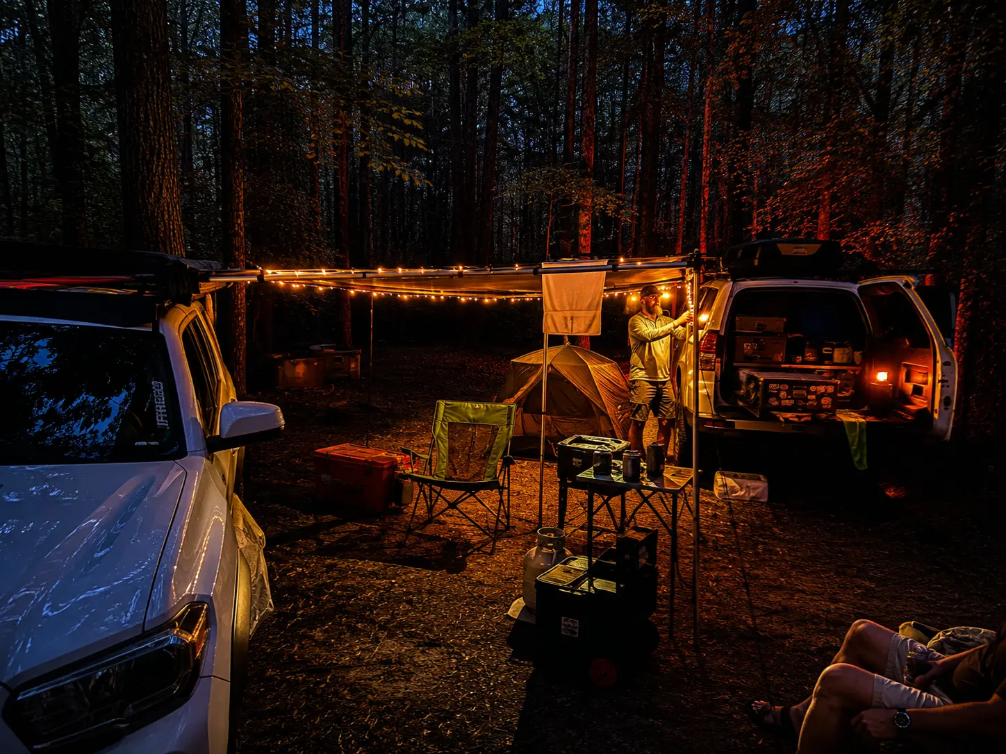 Overland camp setup lit by string lights in the woods